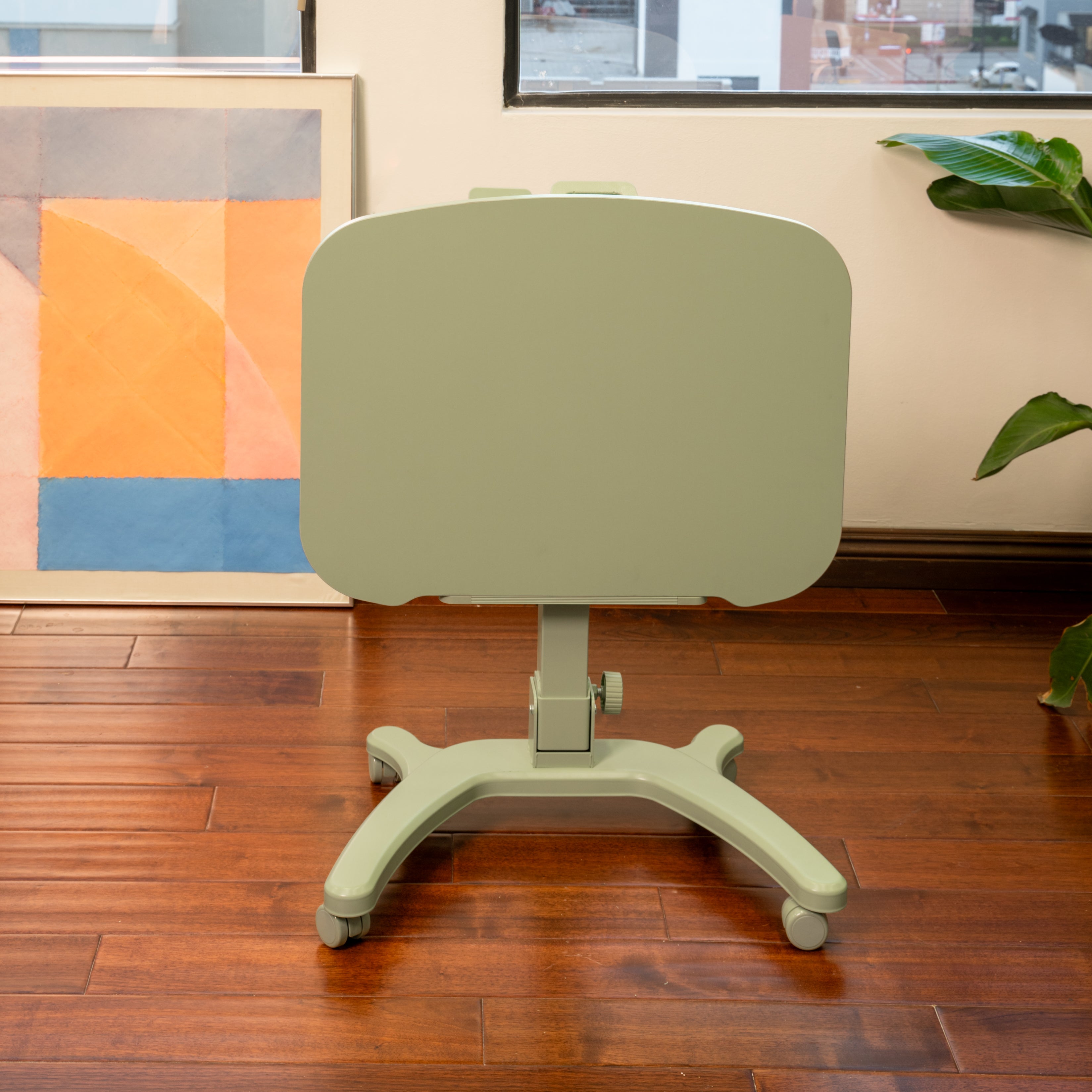 sage mobile desk in a room with wooden floor and colorful abstract art on the wall.
