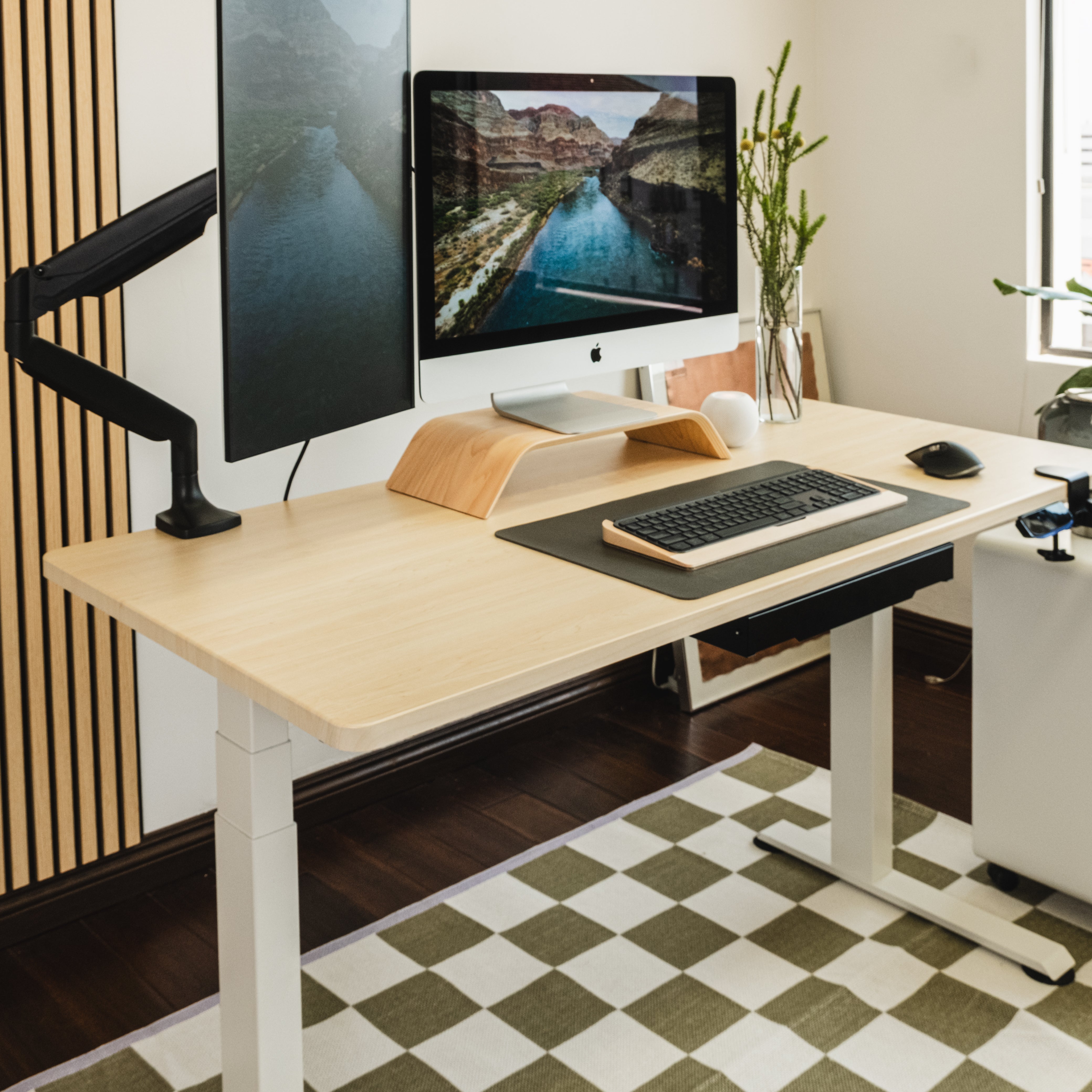 Modern home office setup with a standing desk, computer monitors, and office supplies.