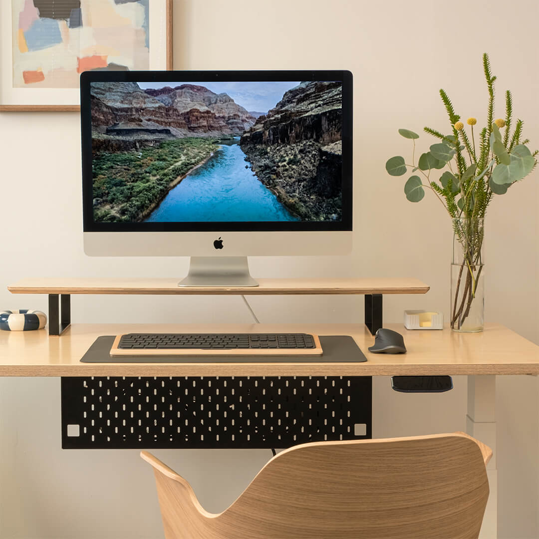 Modern home office setup with a computer monitor, keyboard, and mouse on a wooden desk.