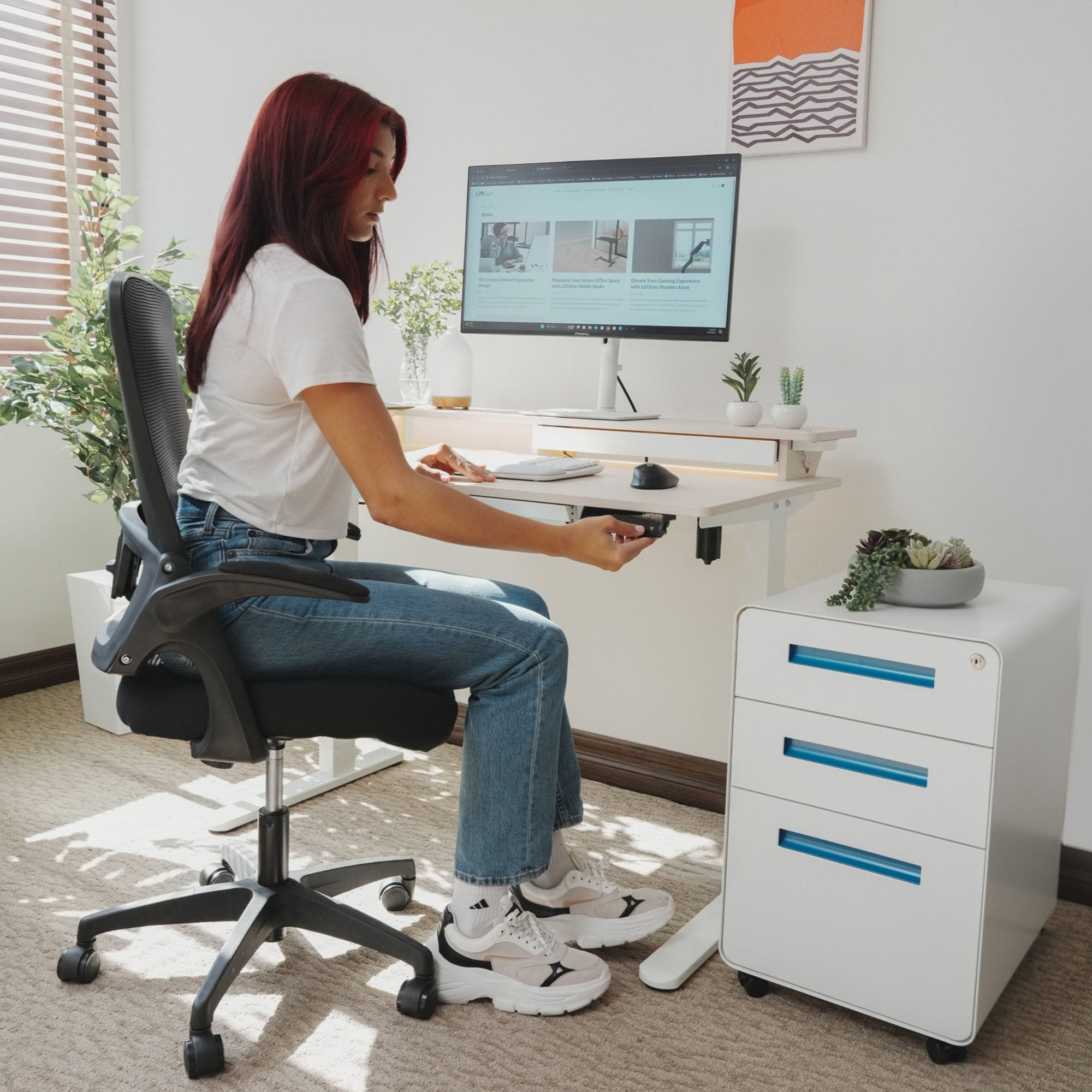 Woman sitting at LiftSync Shelfy electric standing desk with LED lighting, built-in shelf, storage drawer