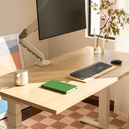 Modern office desk setup with a computer monitor, keyboard, mouse, mug, and notebook.