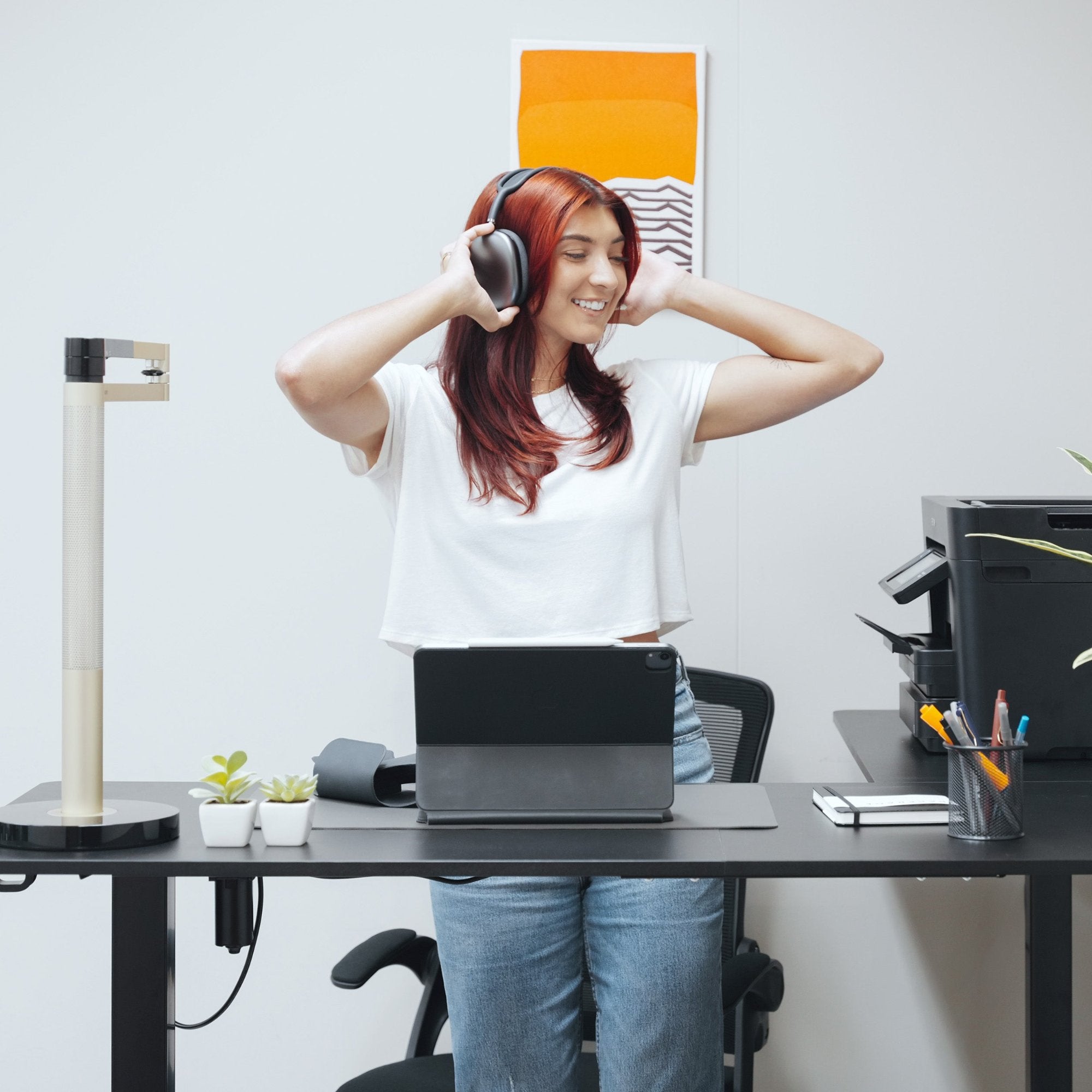 woman standing at LiftSync Pro L standing desk in black with L-shape design