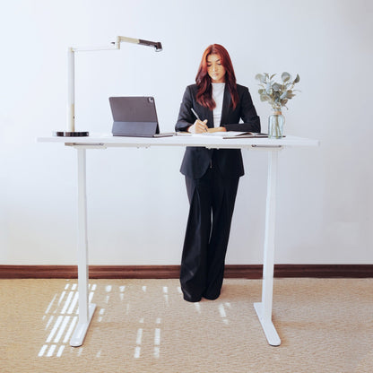 woman standing at LiftSync Pro electric standing desk with white desktop and white desk frame