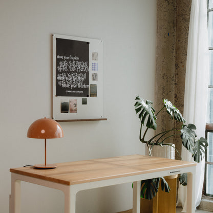 Modern interior with a wooden desk, lamp, and plant near a window.
