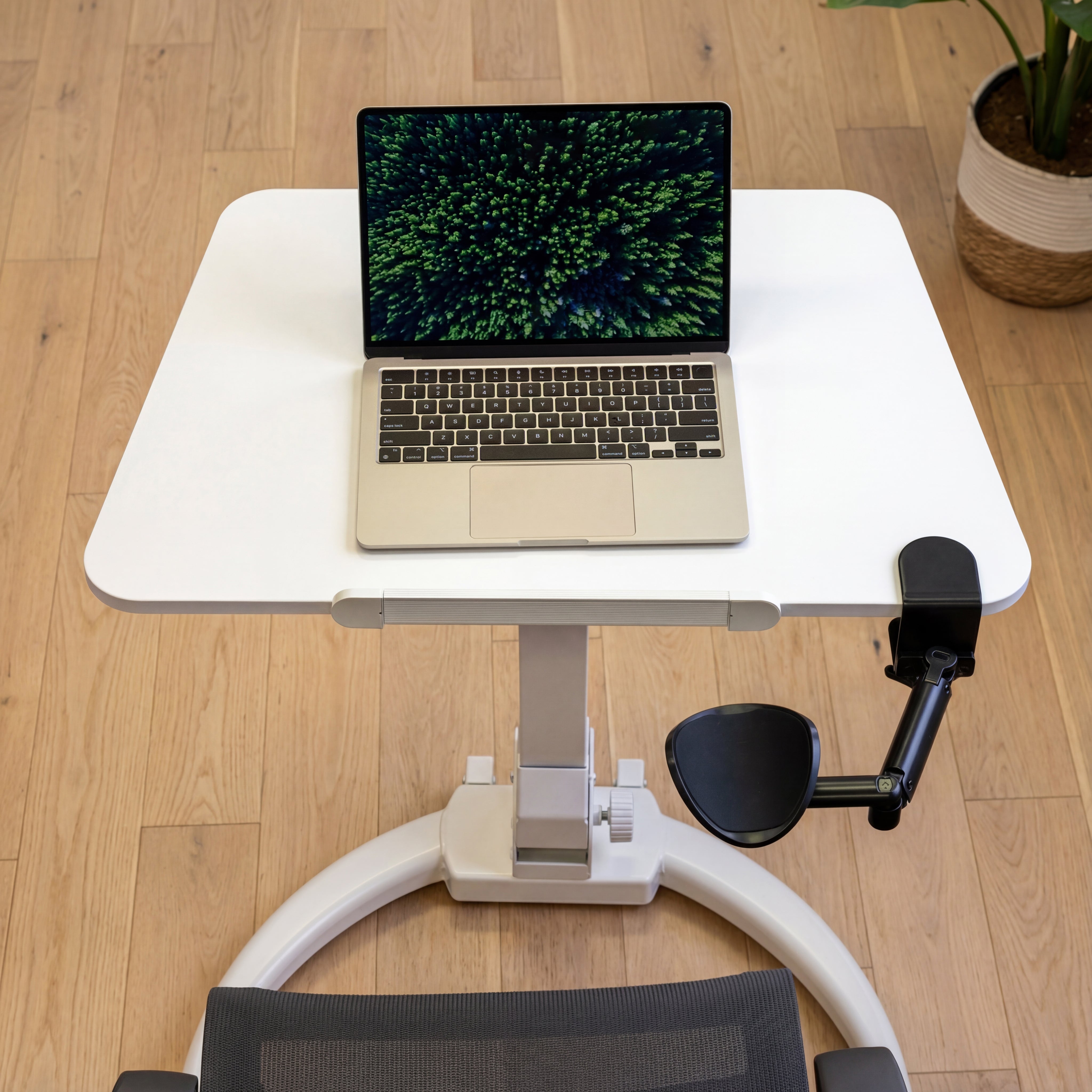 Laptop on an adjustable mobile standing desk with a chair in a home office setting.