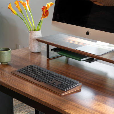 Wooden desk with computer monitor, keyboard, and decorative elements on a neutral background