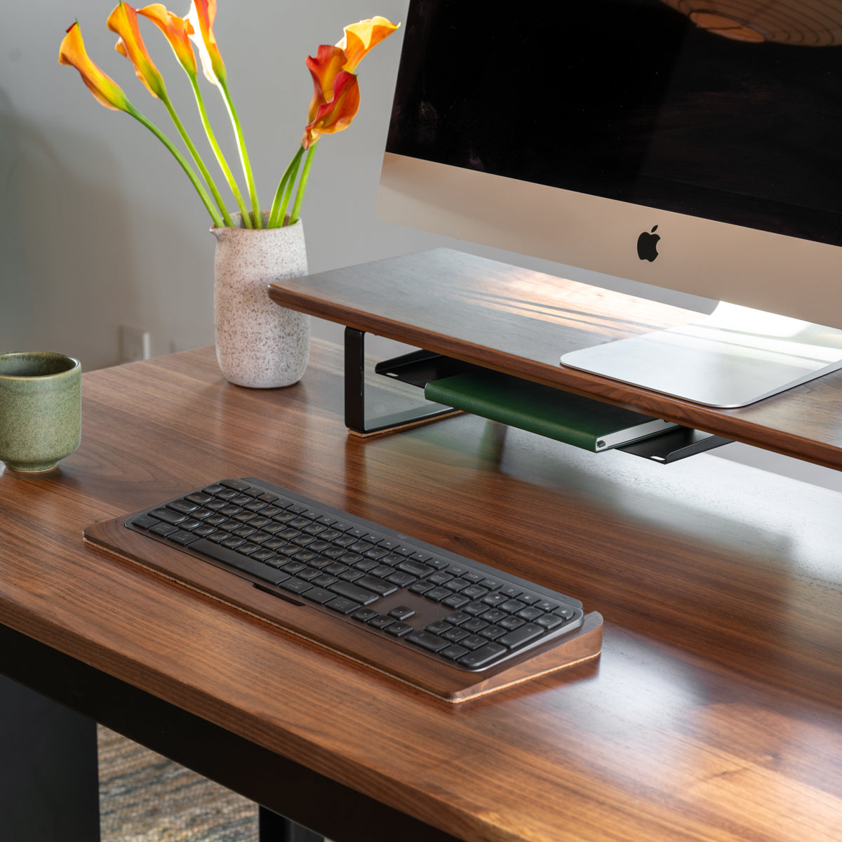 Wooden desk with computer monitor, keyboard, and decorative elements on a neutral background