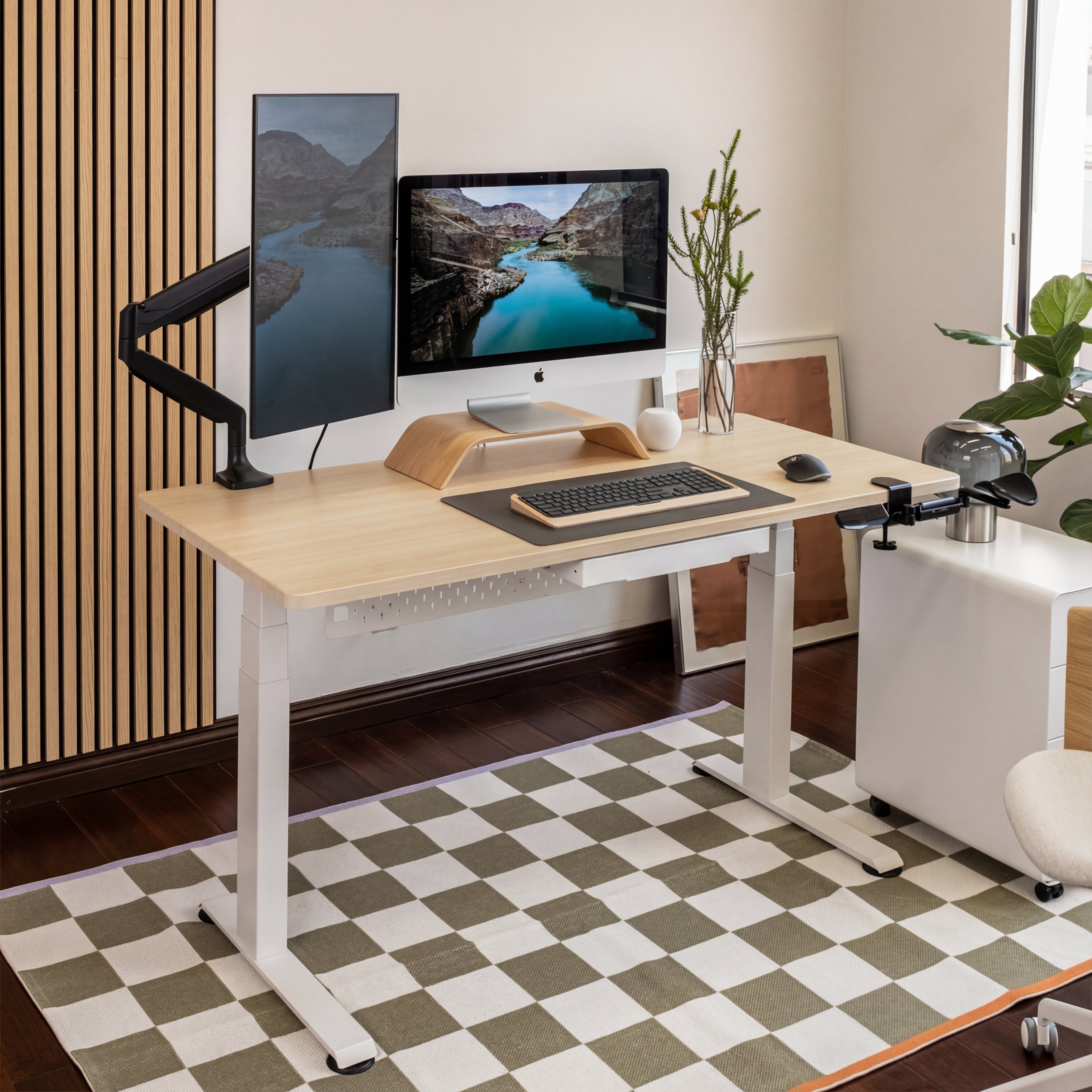 Modern home office setup with a standing desk, computer monitors, and office chair.
