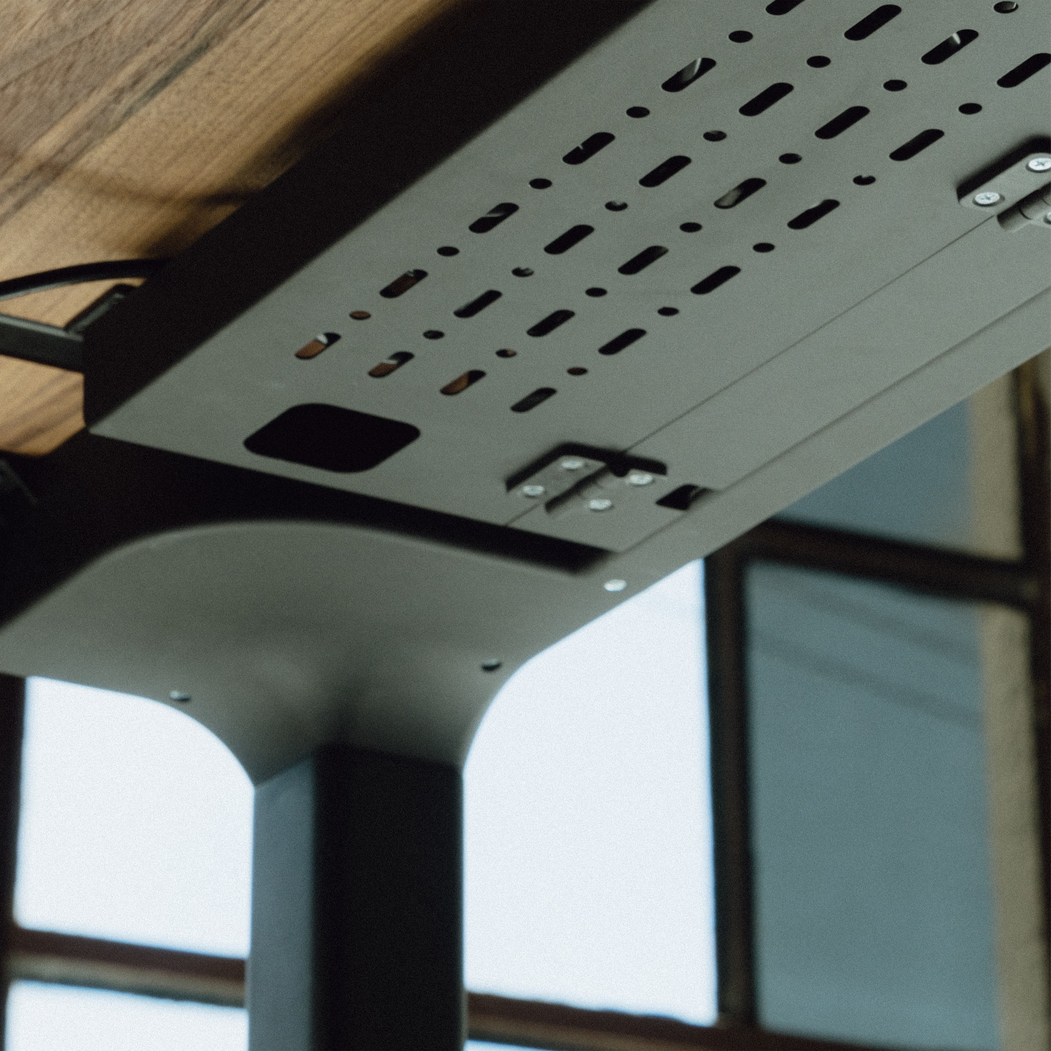 Ceiling-mounted light fixture with perforated design in a room with large windows.