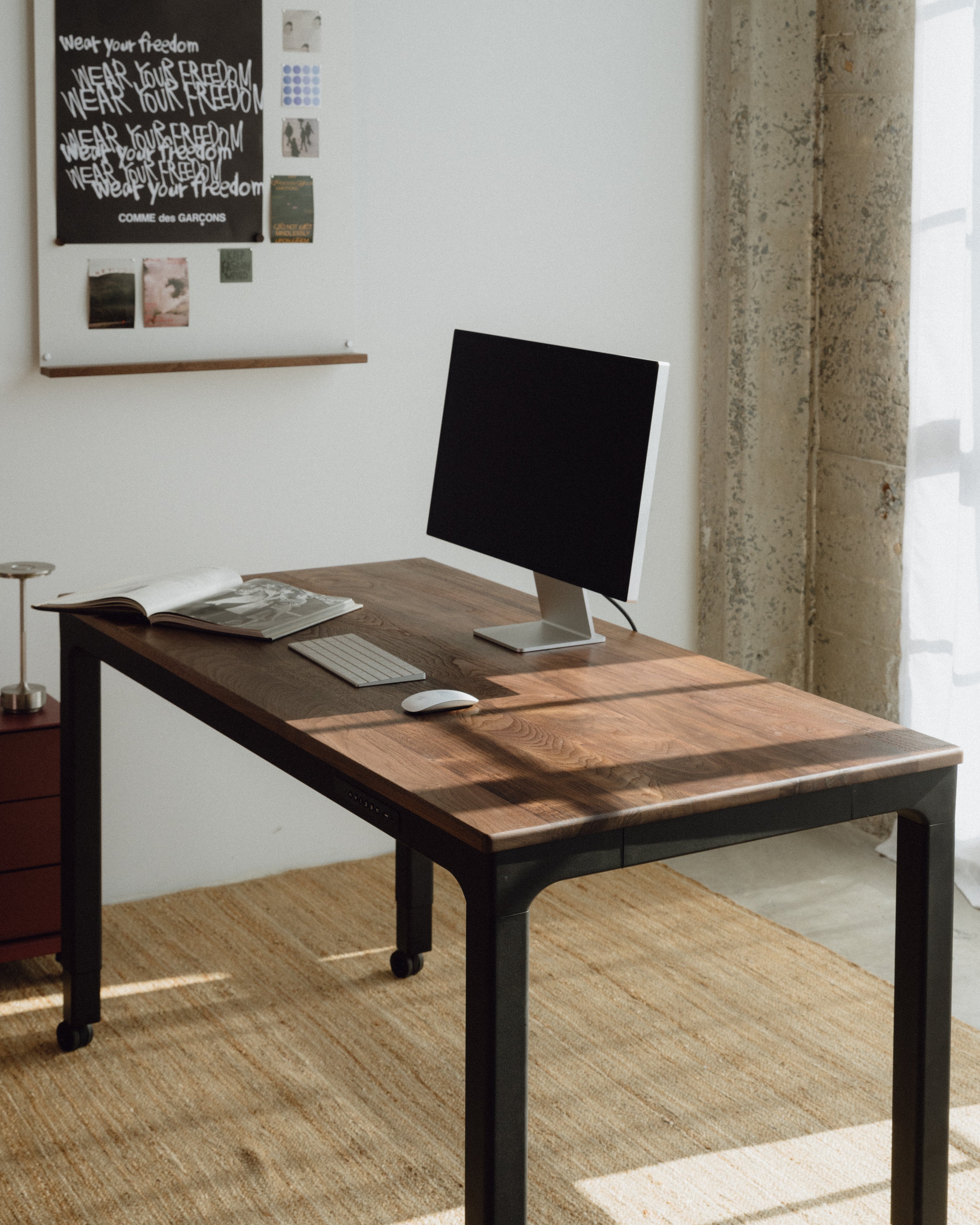 Wooden desk with a vase of dried plants against a striped wall.