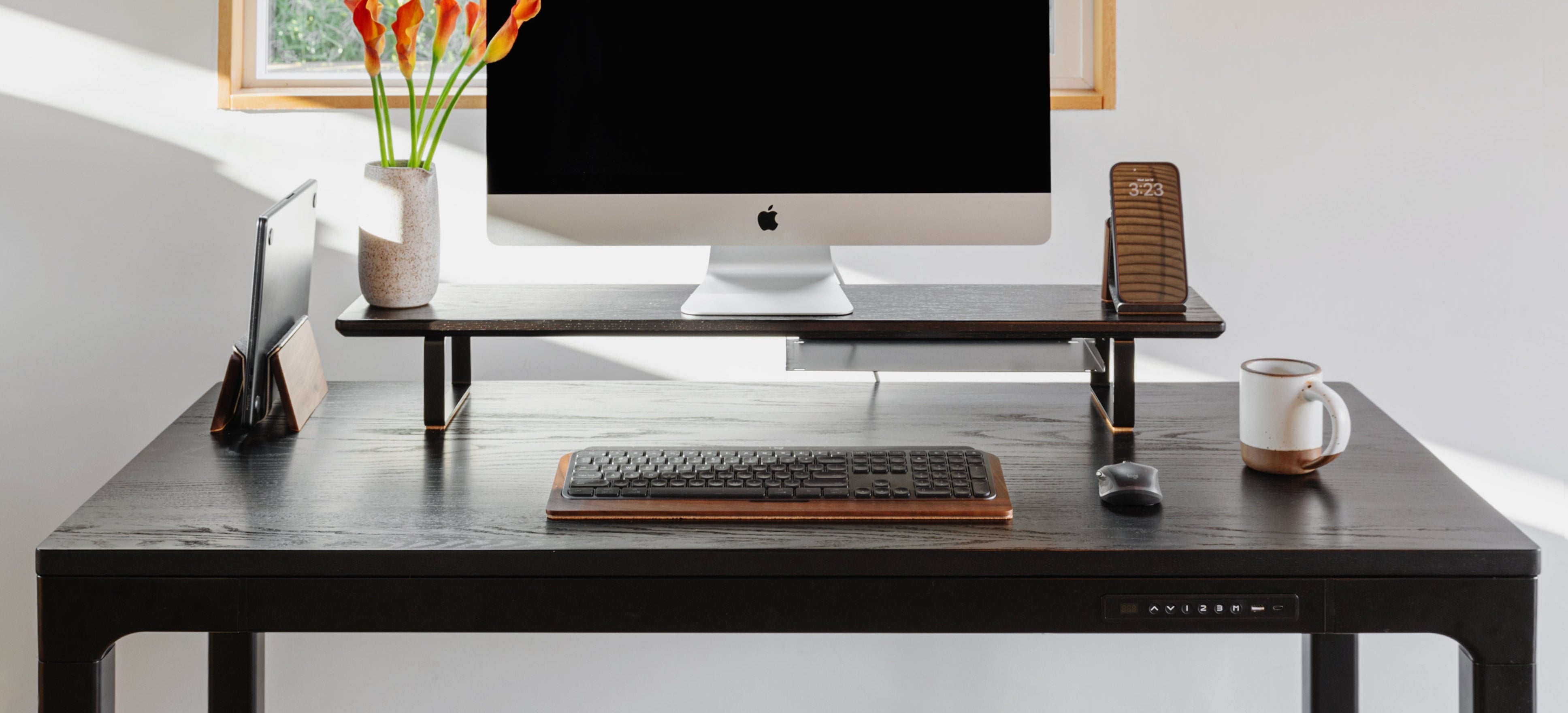 Modern office desk setup with computer monitor, keyboard, and mug in a bright room.